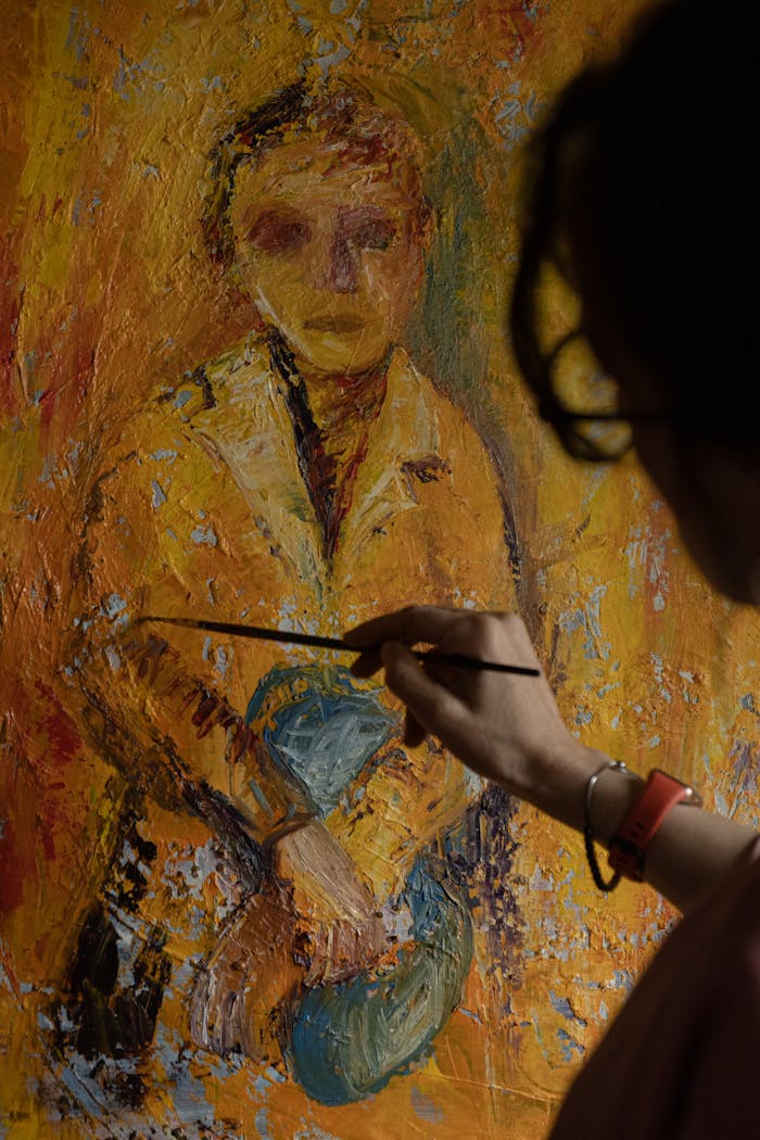 An artist's hand captures a portrait with a brush on a vibrant textured canvas.